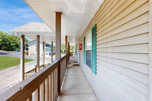 Enjoy the serene view from this covered porch with a street and grassy area in the background.