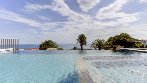 A clear blue pool with a view of the sea and palm trees. - Villa Atalaya (Peñíscola)