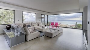A modern living room with a large sectional sofa, a glass coffee table, and a view of the ocean. - Villa Atalaya (Peñíscola)