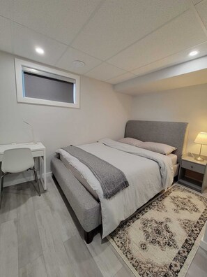 Un dormitorio con cama, escritorio y mesita de noche.