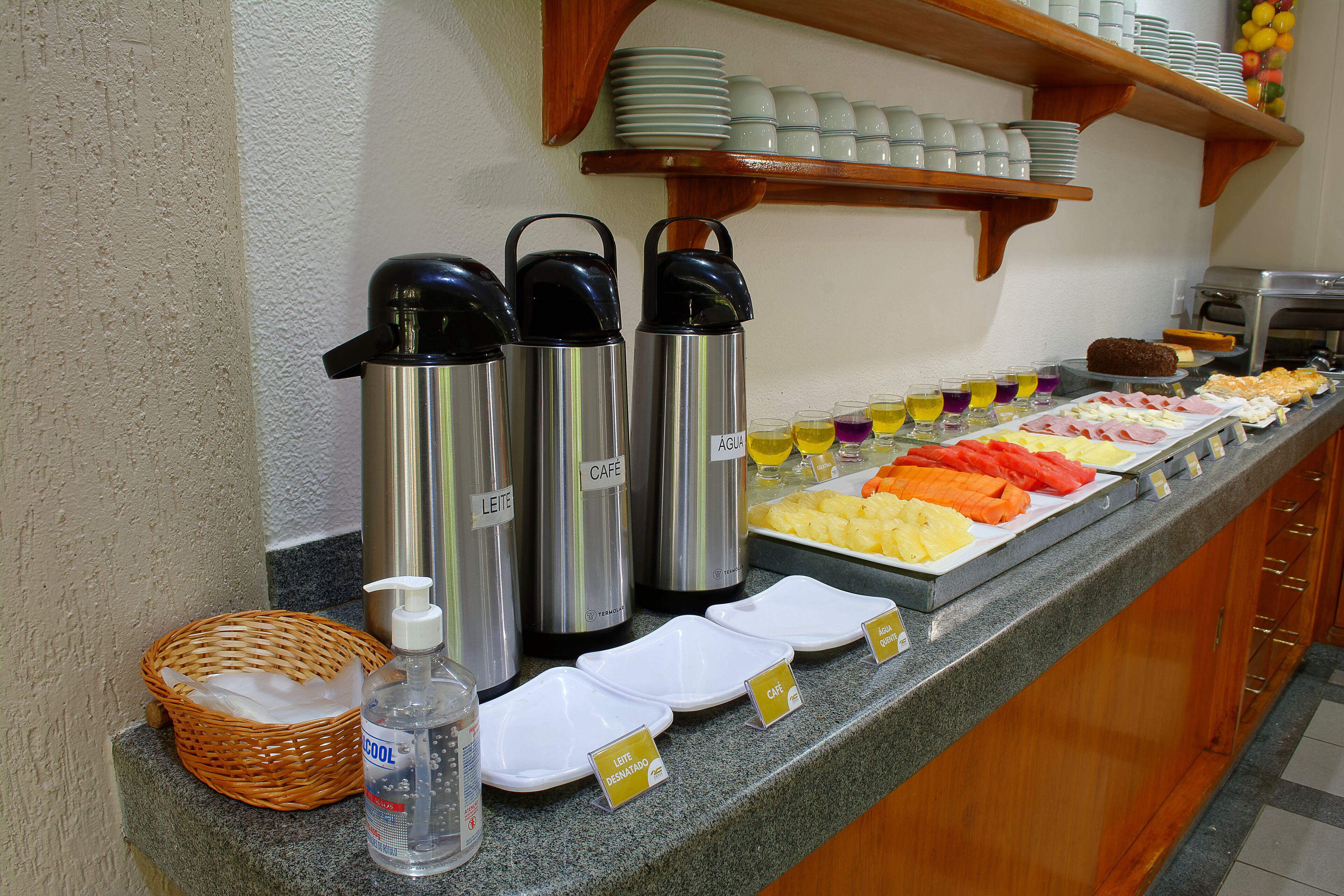 A buffet counter with various food items and labeled containers for beverages.