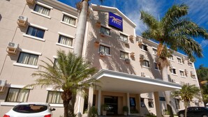 Un hotel con fachada plana, varios balcones y un acceso cubierto.