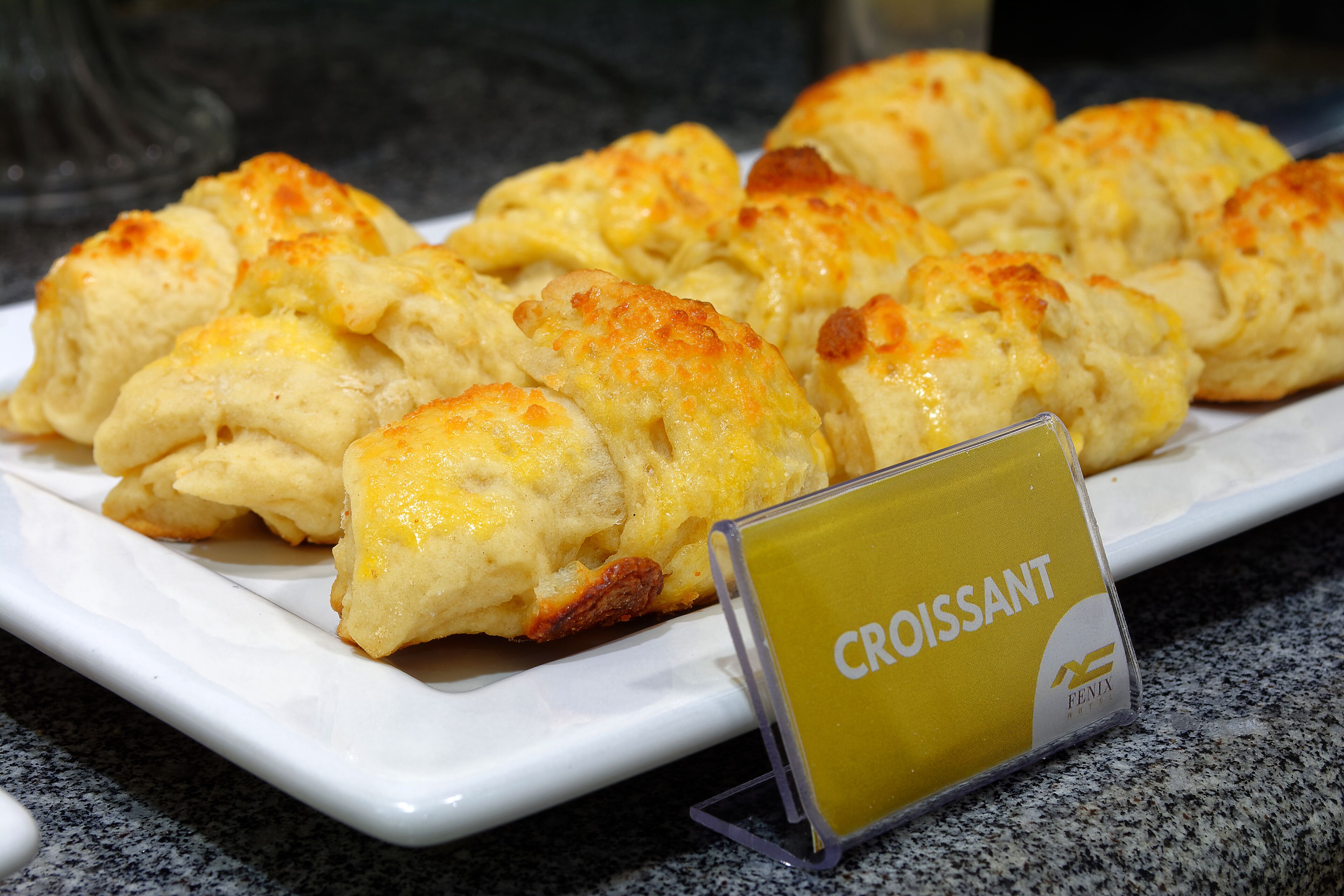 A plate of croissants on a white plate with a sign that reads "Croissant".
