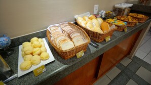 Una mesa de buffet con panes y pasteles varios.