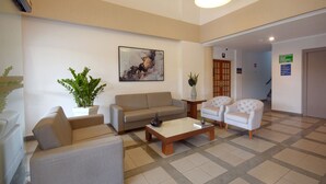 Amplia sala de estar con un sofá, sillones, una mesa de centro y una planta en maceta.