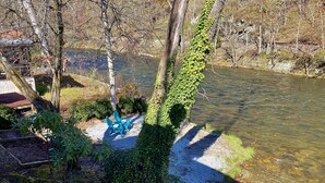 Un sendero de grava que lleva a una silla azul junto a un río, rodeado de árboles y follaje.