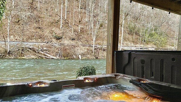 Un jacuzzi con vistas a un río y un bosque.