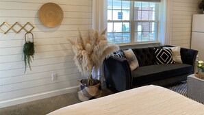 A cozy living room with a dark sofa, a woven basket with pampas grass, and a round woven wall hanging. - Modern, cozy, Studio Apartment (Ochlocknee)