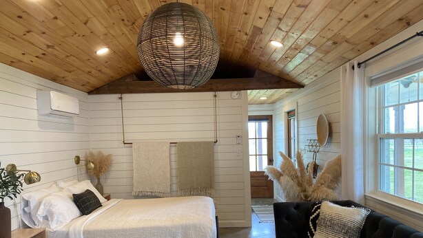 A bedroom with a bed, a black sofa, a wooden ceiling, and a large window. - Modern, cozy, Studio Apartment (Ochlocknee)