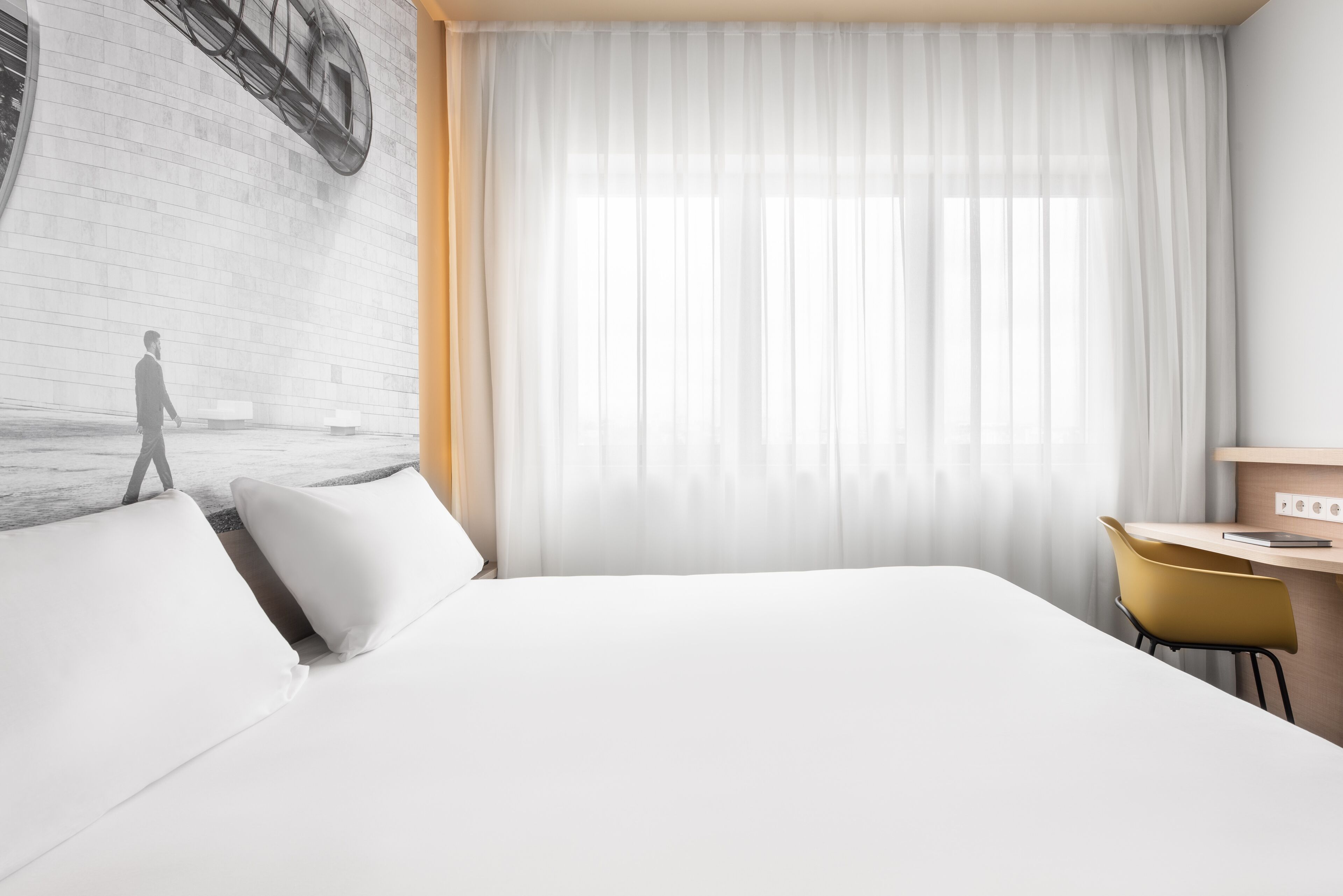 Ein modernes Hotelzimmer mit einem großen Bett, einem Schreibtisch und einem Stuhl.