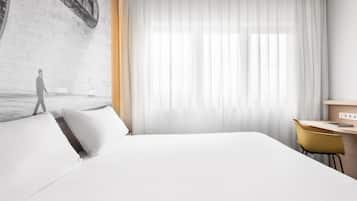 Ein modernes Hotelzimmer mit einem großen Bett, einem Schreibtisch und einem Stuhl.