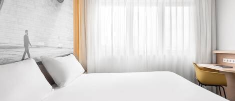 Una habitación de hotel moderna con una cama grande, un escritorio y una silla.