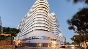 A modern hotel with a curved facade, multiple floors, and a prominent entrance with a staircase.