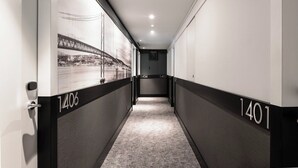 A hallway with black and white walls, numbered doors, and a carpeted floor.