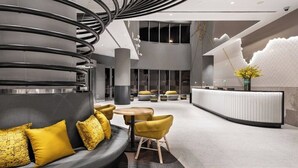 A modern lobby with a curved sofa, round tables, and a reception desk.