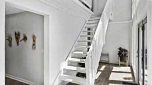 A staircase with white railings, a small plant on a stand, and wall-mounted decorations. -  Above Asheville, Art House  (Fairview)