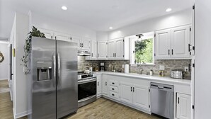 A modern kitchen with white cabinets, stainless steel appliances, and a wooden floor. -  Above Asheville, Art House  (Fairview)