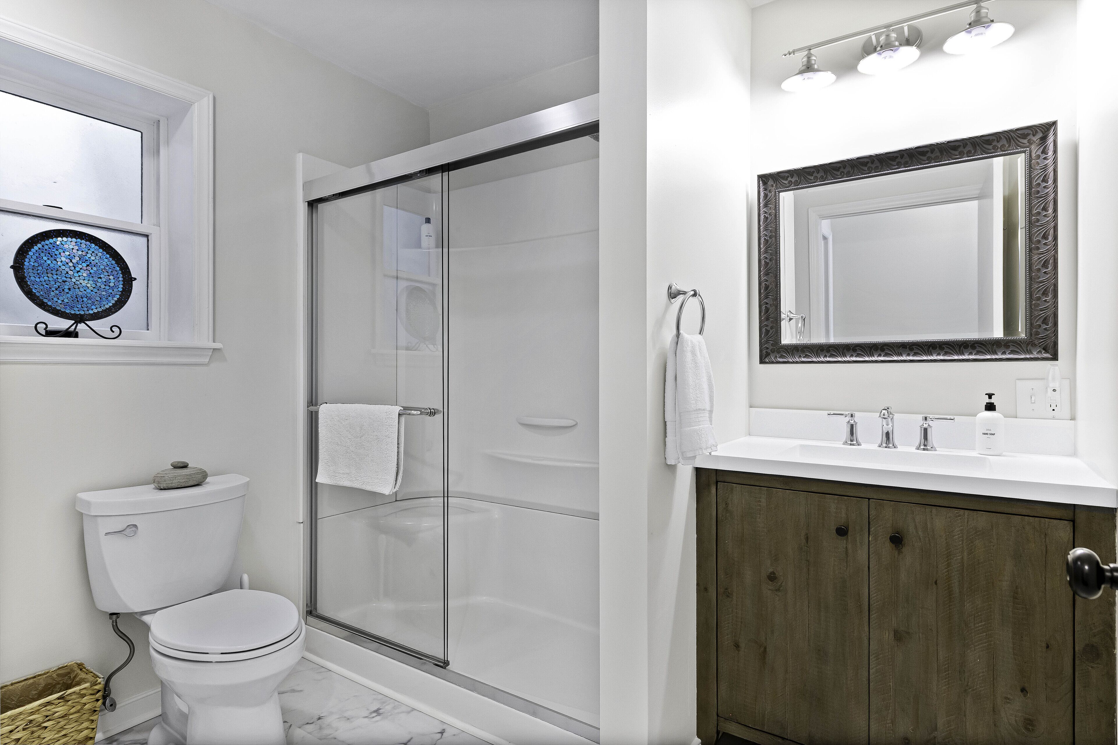 Un baño con inodoro, ducha y tocador con espejo.