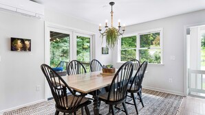 A dining room with a wooden table and black chairs, large windows with a view of greenery, and a chandelier. -  Above Asheville, Art House  (Fairview)