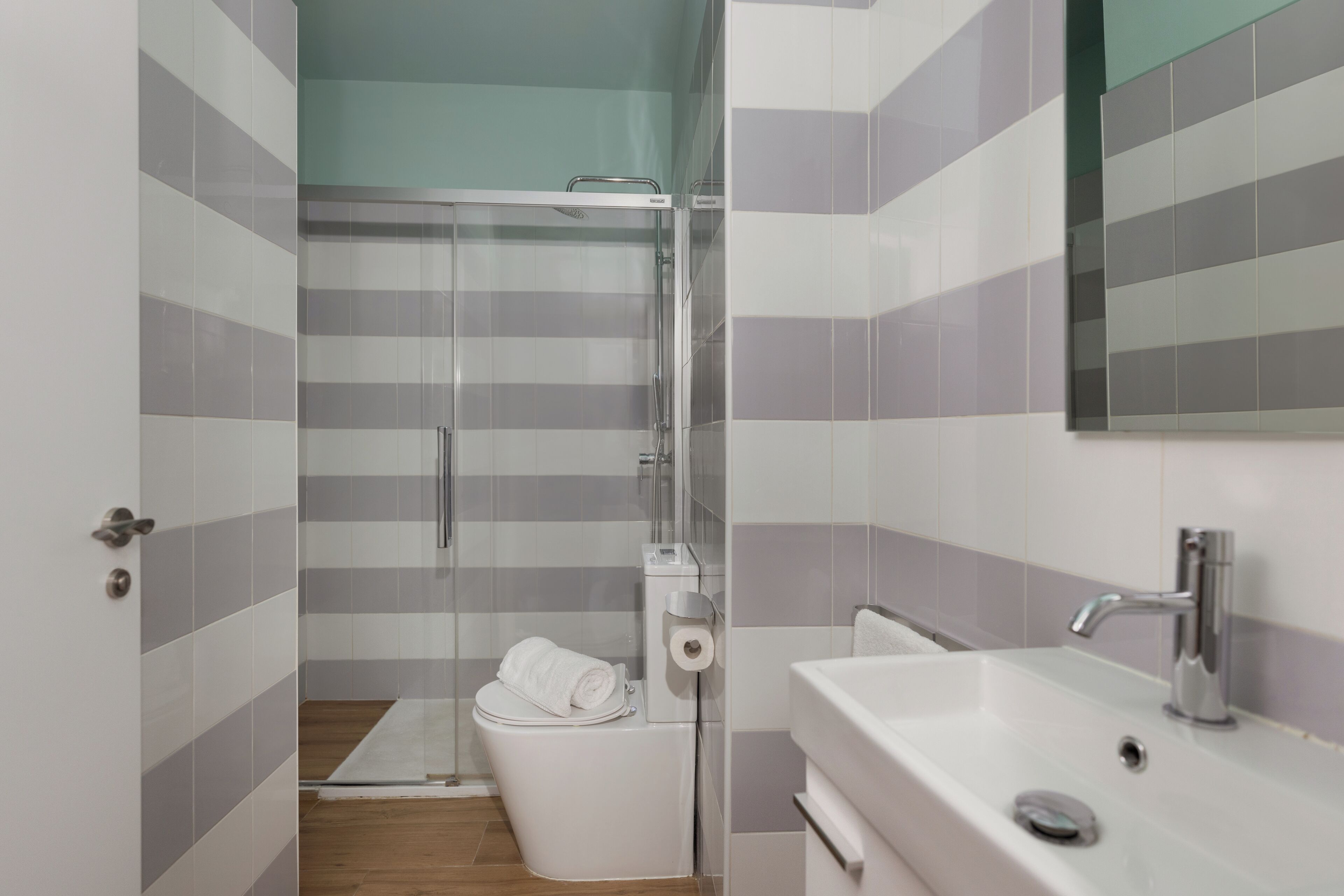 A modern bathroom with a shower, toilet, and sink.