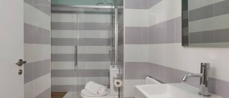 A modern bathroom with a shower, toilet, and sink.