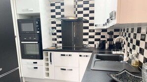 Eine moderne Küche mit schwarz-weißer Schachbrettfliesenrückwand, Edelstahlgeräten und weißen Schränken.