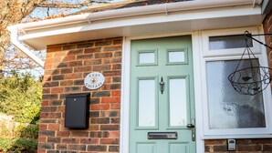 A brick house with a green door, a mailbox, and a hanging light fixture. - Cosy Cottage (Bexhill-on-Sea)