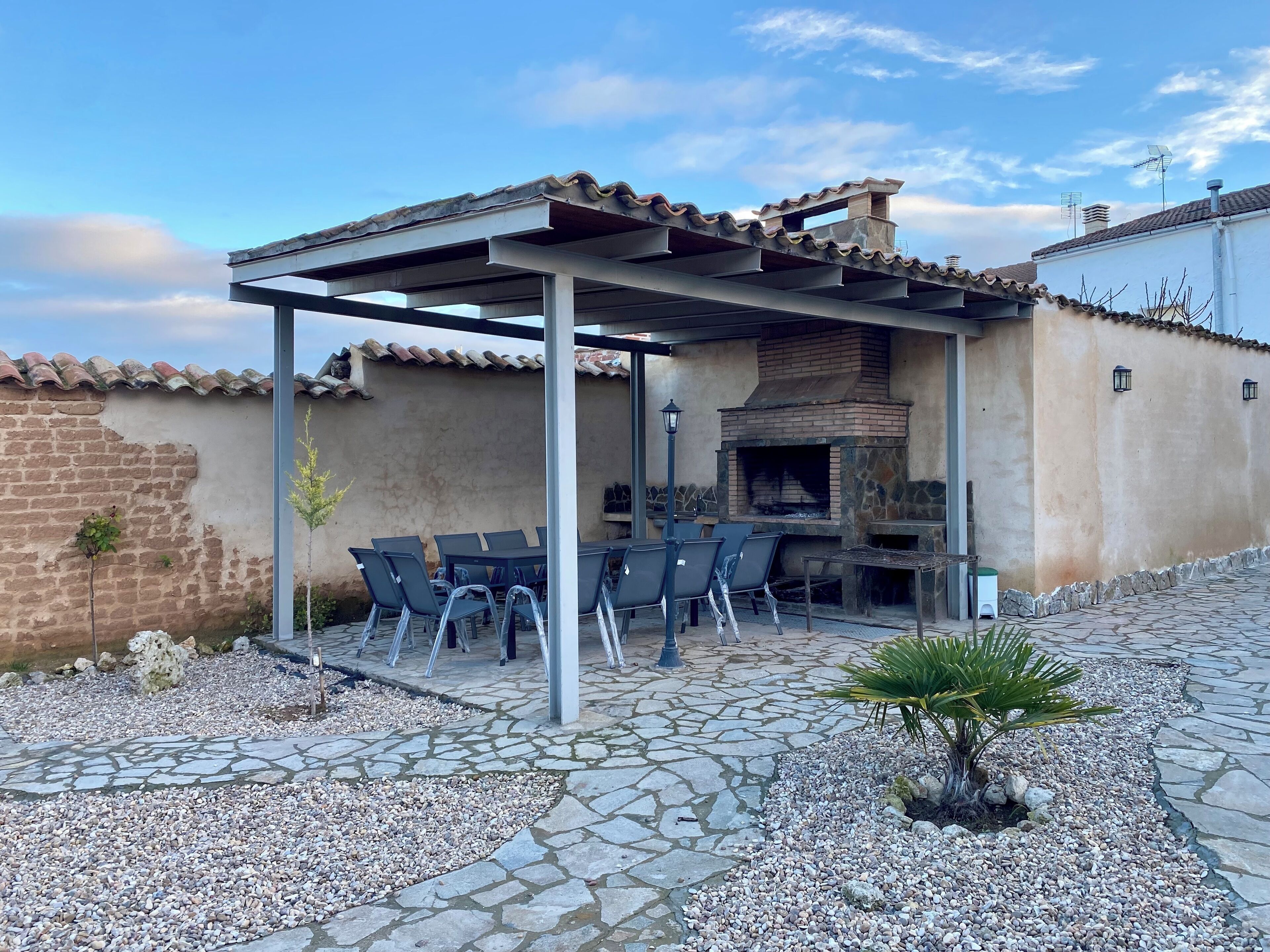 An outdoor patio with a pergola, stone flooring, and a brick oven.