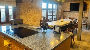Une cuisine dotée d’un plan de travail en granit, d’une cuisinière encastrée et d’un coin repas avec une table et des chaises.
