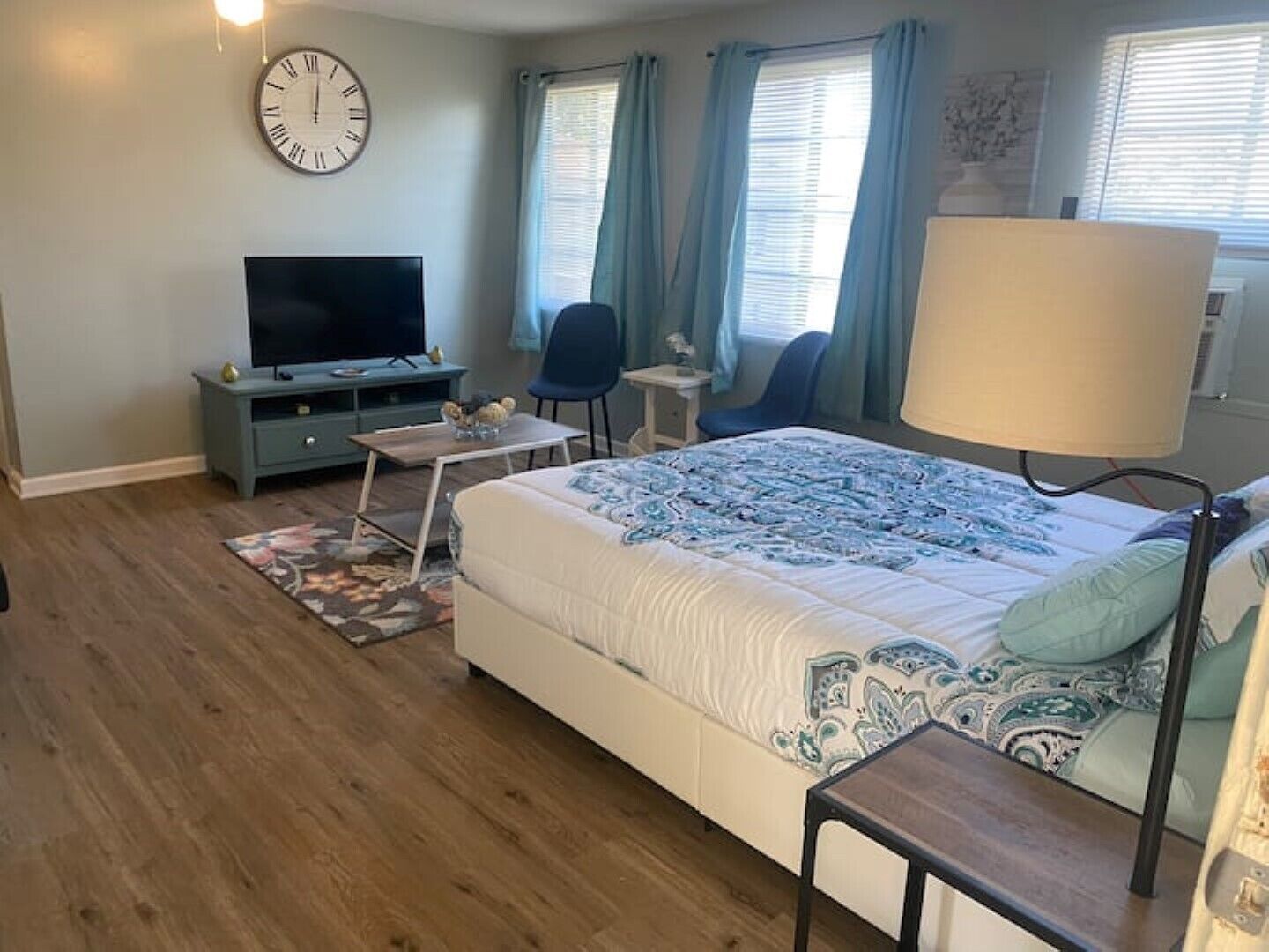 Ein Schlafzimmer mit einem Bett, einem Fernseher, einem Schreibtisch und einem Sessel.