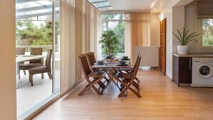 A modern kitchen with a built-in washing machine, a dining area with a table and chairs, and large windows offering a view of the outdoors. - A Private Haven: Hera with Secluded Pool and Garden (Kassandra)