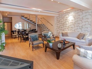 Un salon moderne avec un escalier, un coin repas et un canapé.