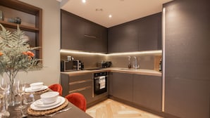 A modern kitchen with dark wood cabinets, a built-in oven, and a countertop with a coffee maker.