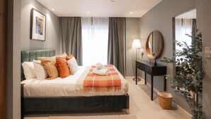 A modern bedroom with a bed, bedside table, and a mirror.