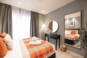 A bedroom with a bed, a bedside table, a mirror, and a window with curtains. - King's 23 (York)