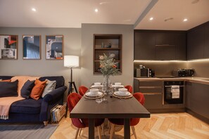 A modern kitchen with dark cabinetry, a built-in oven, and a microwave. - King's 23 (York)