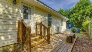 A wooden deck with a staircase leading to a house with white siding and a blue door.