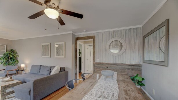 A modern living room with a grey sofa, wooden coffee table, and a ceiling fan.