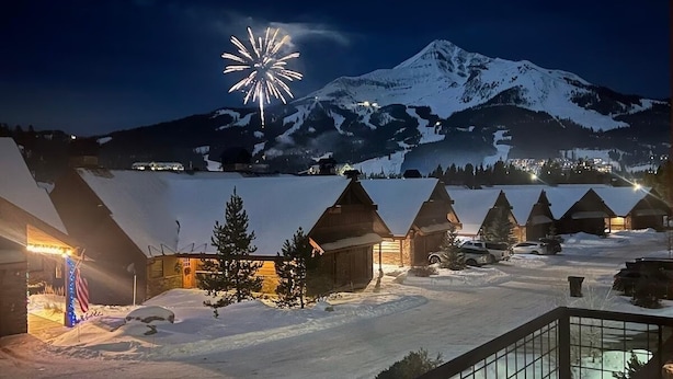 A snow-covered mountain with a lit building and a firework display.