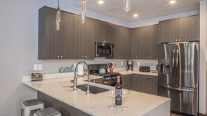 A modern kitchen with a central island, stainless steel appliances, and bar stools.