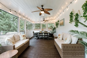 Relax on the shaded deck, surrounded by lush greenery and a tranquil view.