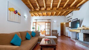 A living room with a wooden ceiling, a sofa with blue cushions, a coffee table, and a fireplace.
