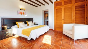 A bedroom with a large bed, wooden wardrobe, and a white sofa.