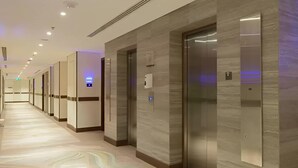 Un pasillo de hotel con ascensores y suelo de mármol.