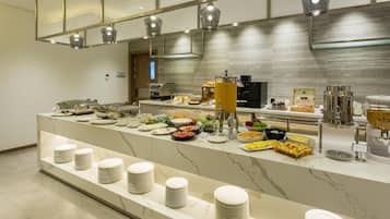 Montaje de bufé con diversas opciones de comida y una máquina de café.