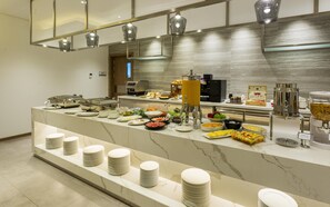 Montaje de bufé con diversas opciones de comida y una máquina de café.