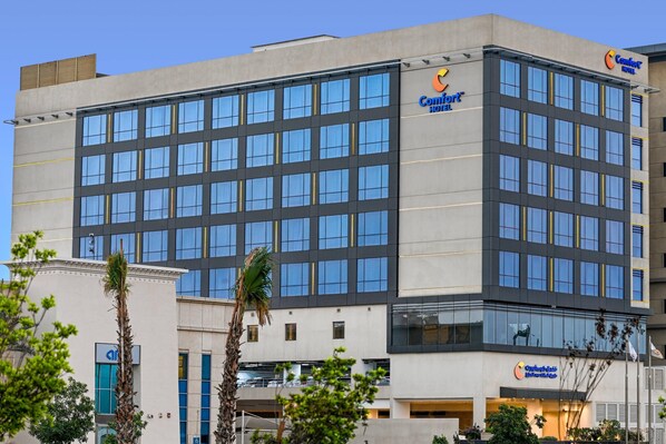 Un moderno edificio de hotel con un llamativo letrero Comfort Inn, varios pisos y grandes ventanales.