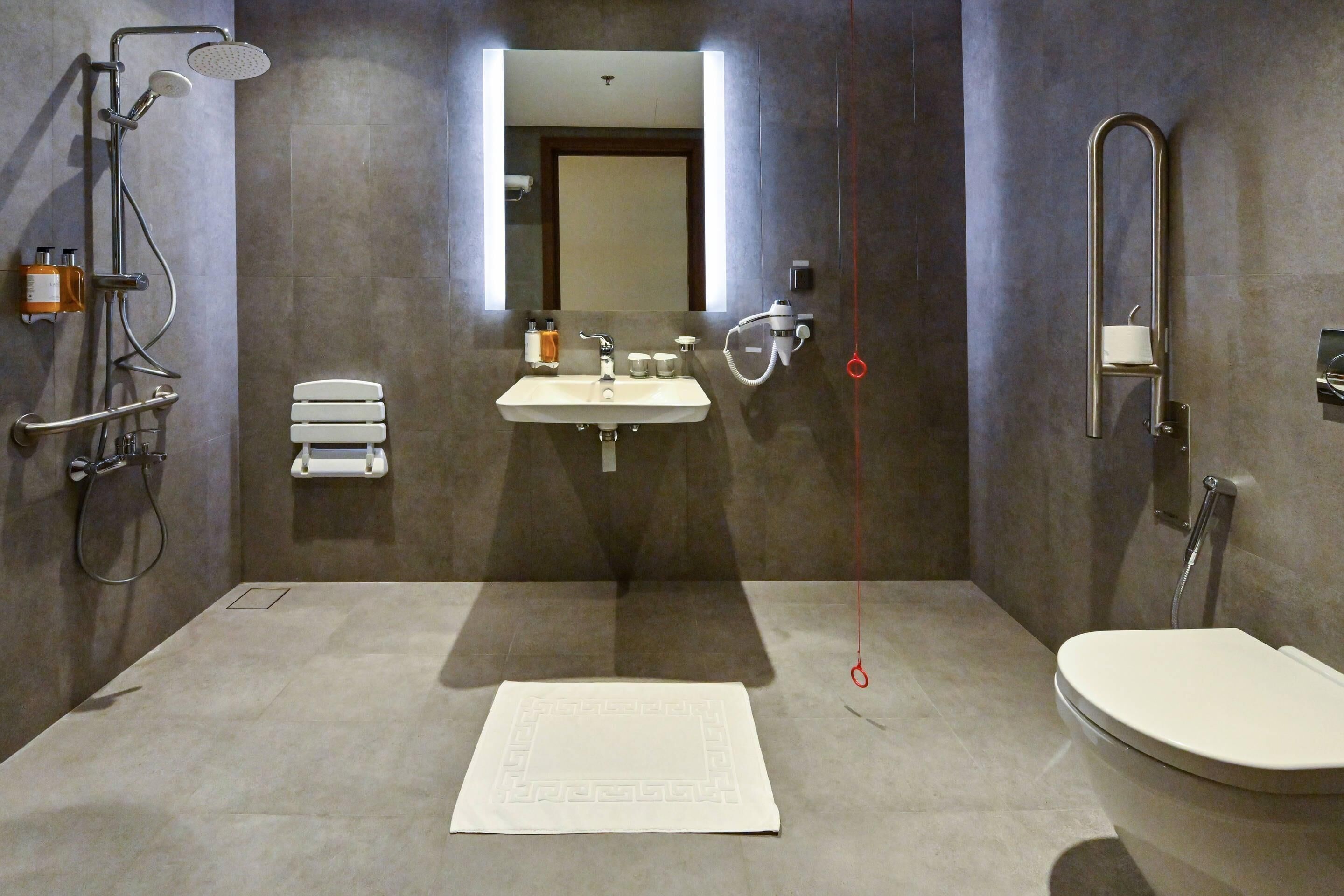 A modern bathroom with a sink, mirror, toilet, and shower.