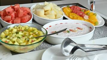 Una mesa con diferentes fuentes de fruta y un bol de ensalada de frutas.