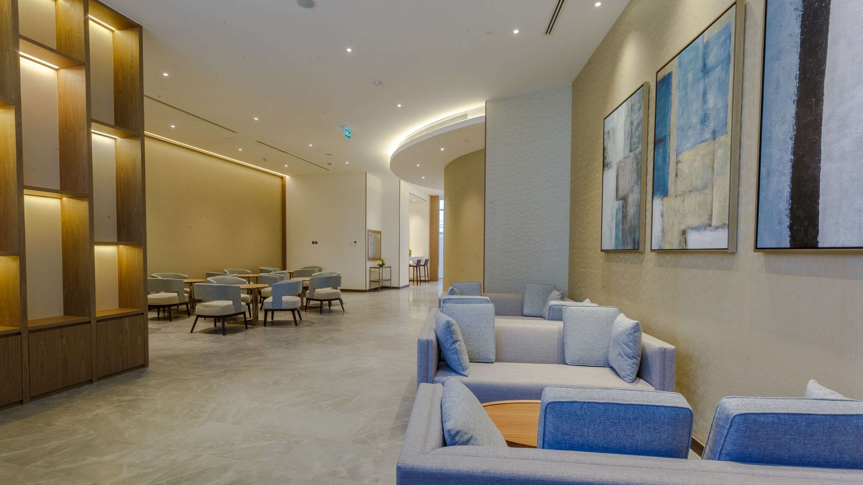 A modern hotel lobby with a seating area, a reception desk, and artwork on the walls.